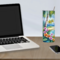 Desk setting with floral tumbler beside open laptop
